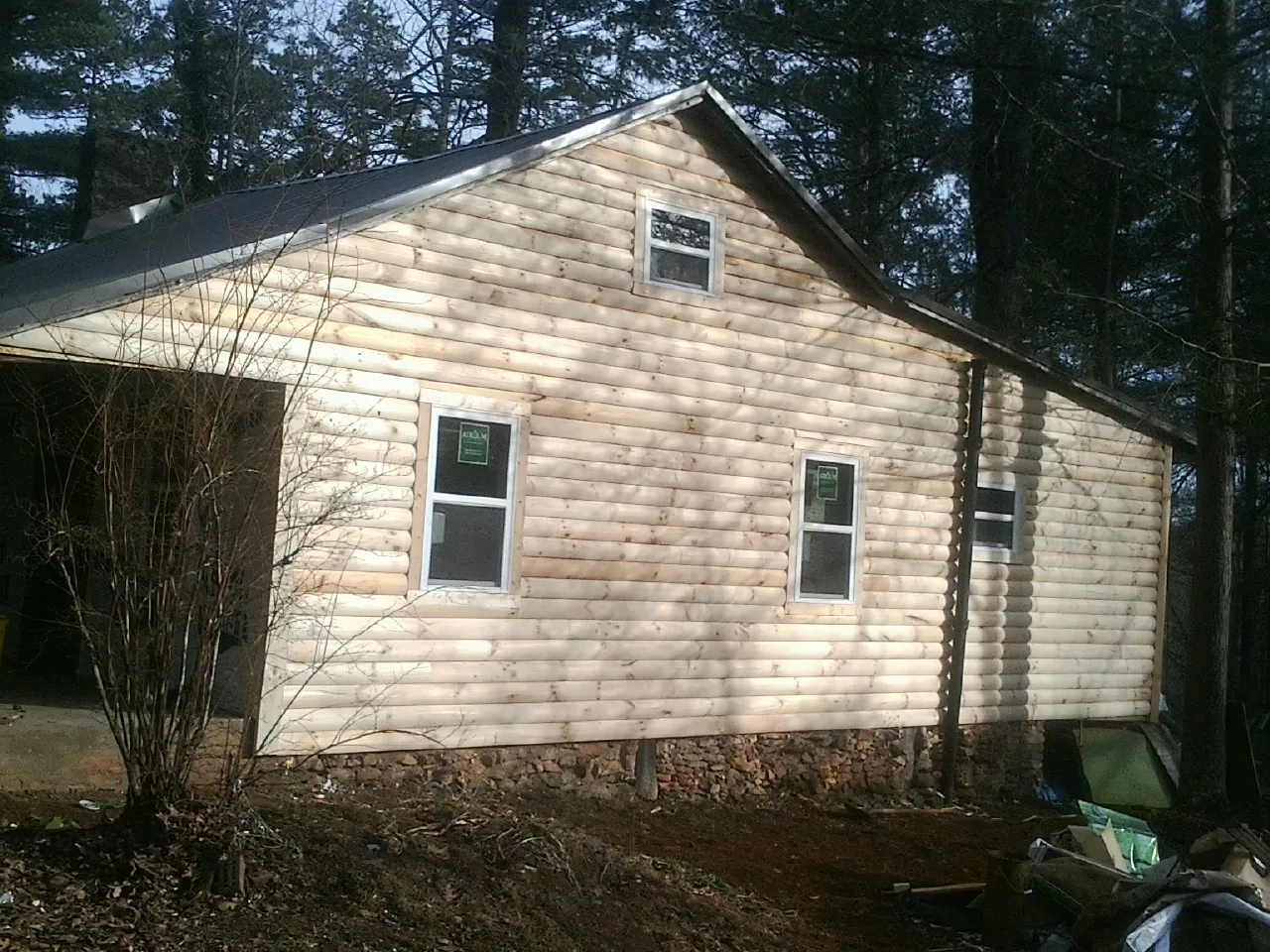 New log siding and dark metal roofing on a gable end in Rome