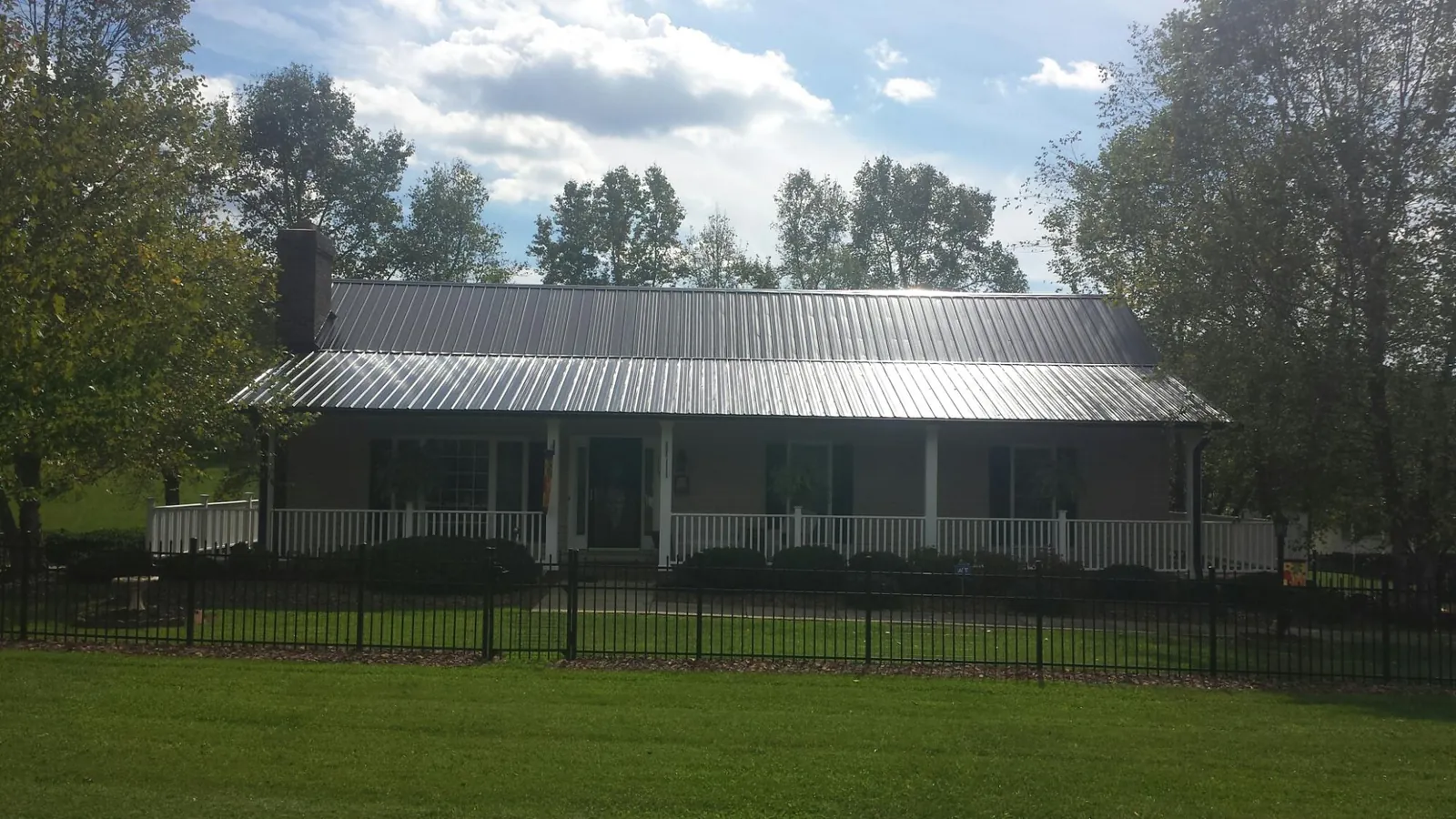 Gray metal roof on a brick ranch with a full width front porch — Gutter Guard Installation work by our crew in Rome