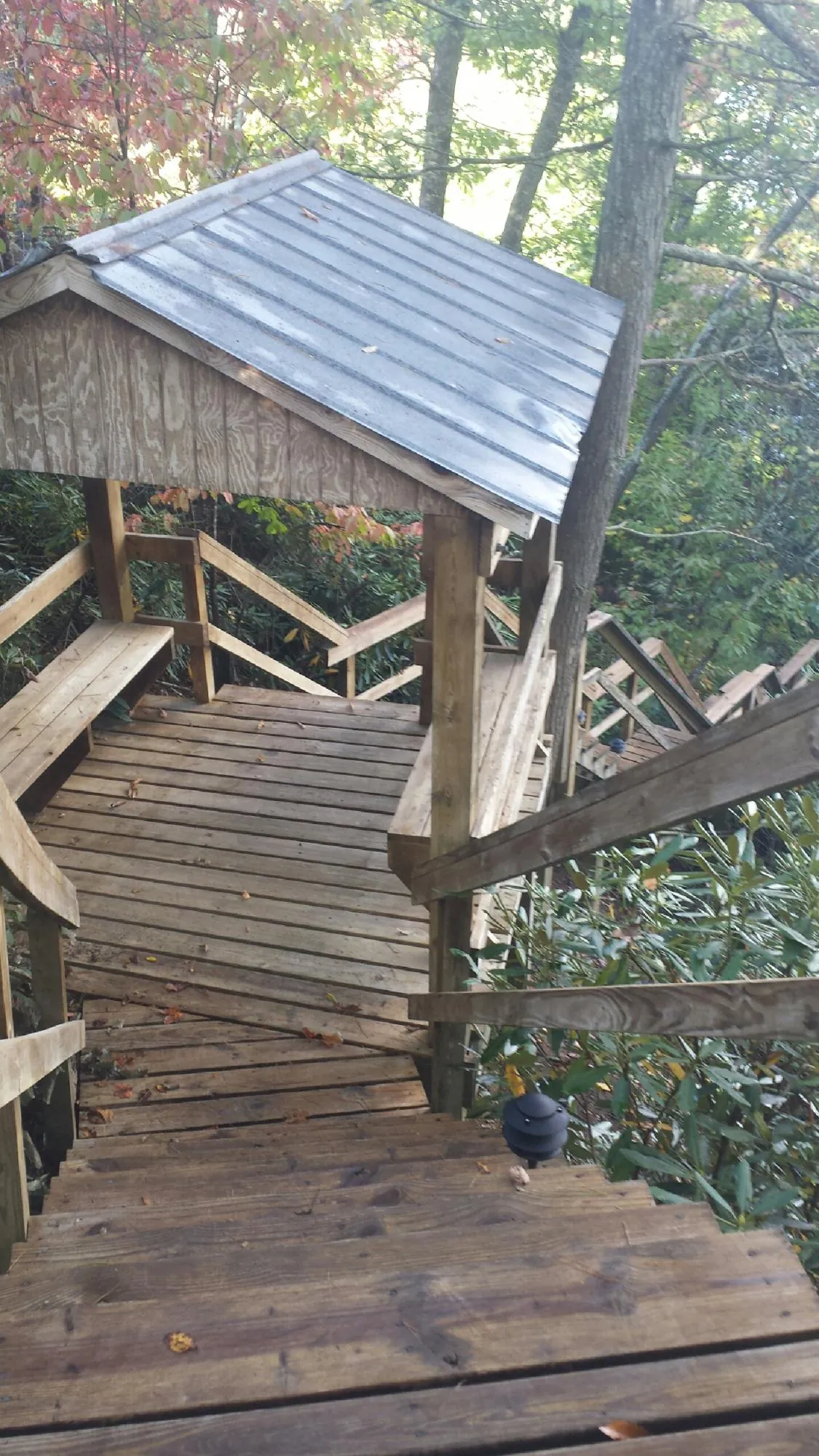 Metal roofed shelter over wooden steps on a wooded walkway — Skylight Repair & Installation work by our crew in Rome